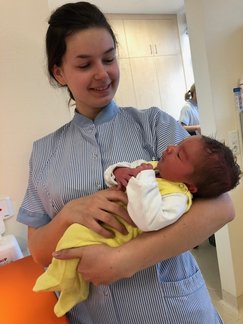 Praktikantin hält ein Neugeborenes