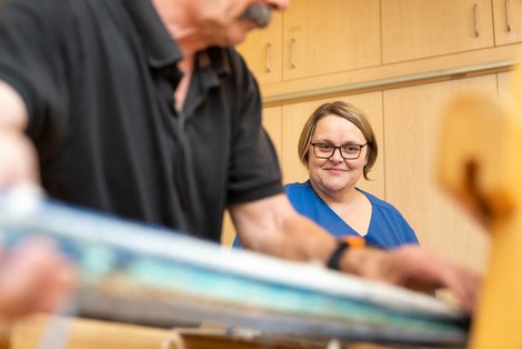 Hier arbeitet Martina Ruhmer, Diplom-Sozialbetreuerin mit Schwerpunkt Behindertenarbeit und Behindertenbegleitung mit einem Bewohner am Webstuhl in der Kreativwerkstatt des Schlosses.