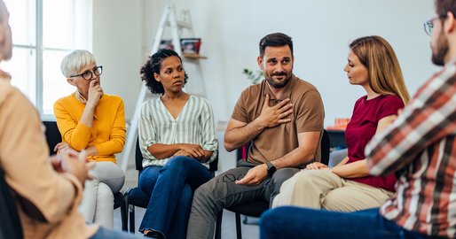 verschiedene Personen sitzen im Kreis und reden miteinander