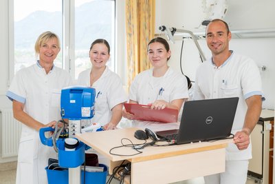 Vier Pflegekräfte im Krankenzimmer mit Laptop und medizinischem Gerät
