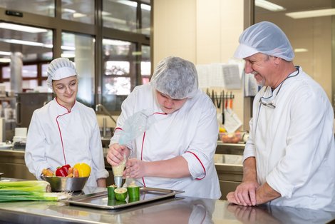 Küchenchef Bruno Ullmann mit den beiden Lehrlingen, die mit viel Freude und Geschick mit dabei sind. 