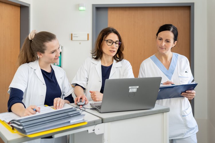 ÄrztInnen und Pflegepersonal schauen sich etwas am Laptop an