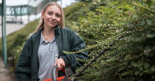 Lehrling Gartenbau beim Heckenschneiden