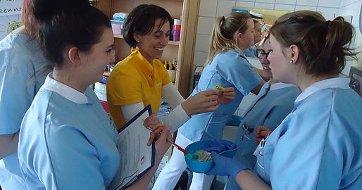 1 Lehrende und mehrere Schülerinnen mit einem Blutproberöhrchen