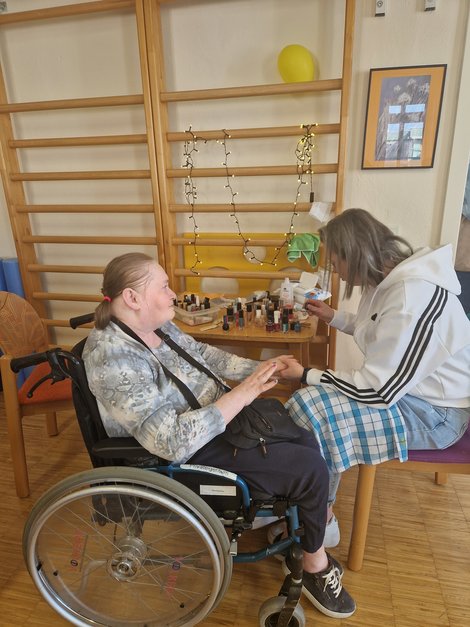 Bewohnerin im Rollstuhl bekommt Maniküre