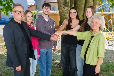 SchuldirektorInnen undSchülerInnen stehen im Halbkreis und reichen sich in der Mitte die Hände