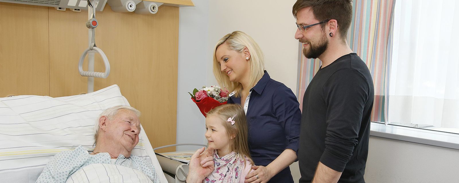 Eltern mit Kind besuchen kranken Großvater im Spital