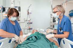 Zwei Pflegerinnen arbeiten an einem Intensivbett mit beatmentem Patienten