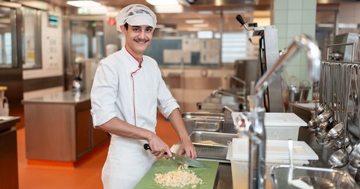 Kochlehrling in der Spitalsküche beim Schneiden