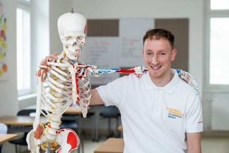 Pflegeschüler Arm in Arm mit Plastikskelett
