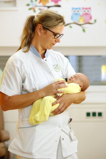 Mitarbeiterin mit Baby in der Hand