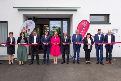 Gruppenfoto vor dem neu eröffneten Gebäude beim Durchschneiden des Bandes