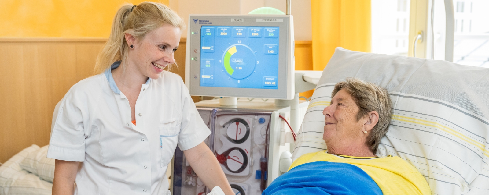Dialyse Patientin und Pflegefachkraft schauen sich lächelnd an