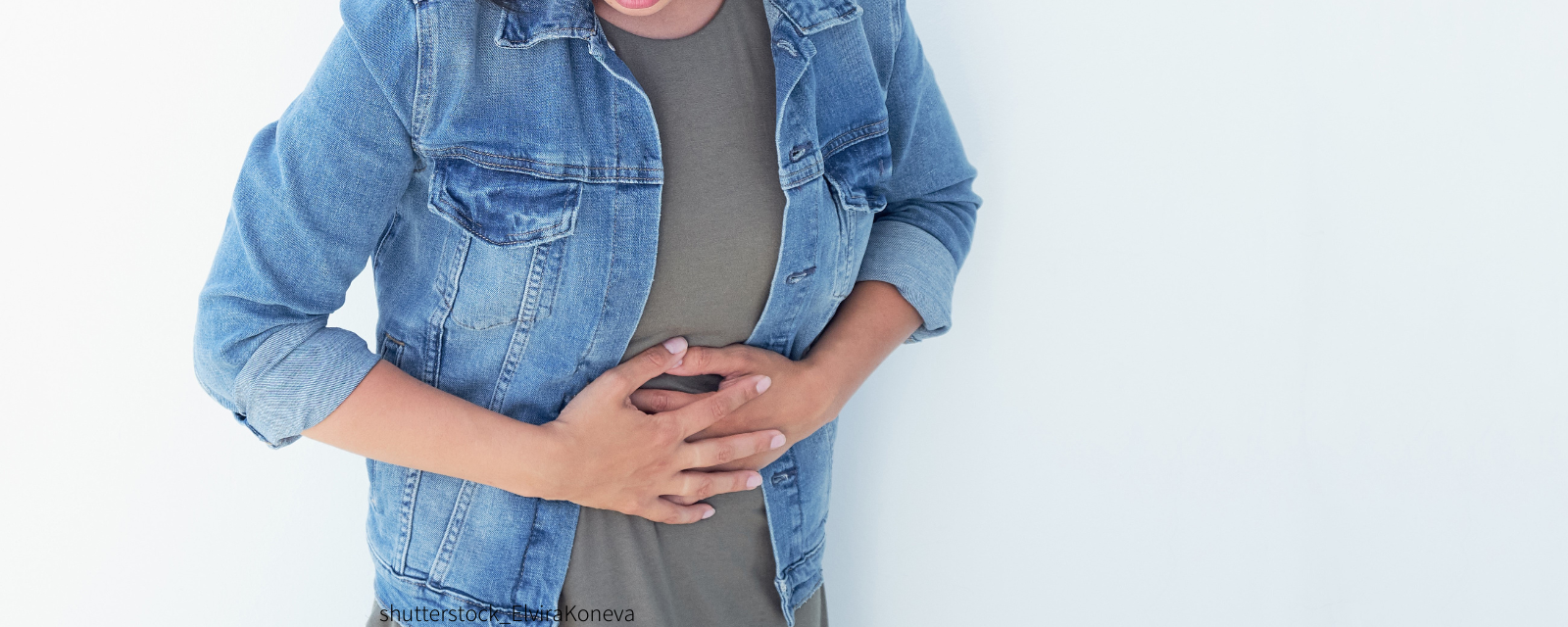 Frau fasst sich vor Schmerz an den Bauch.