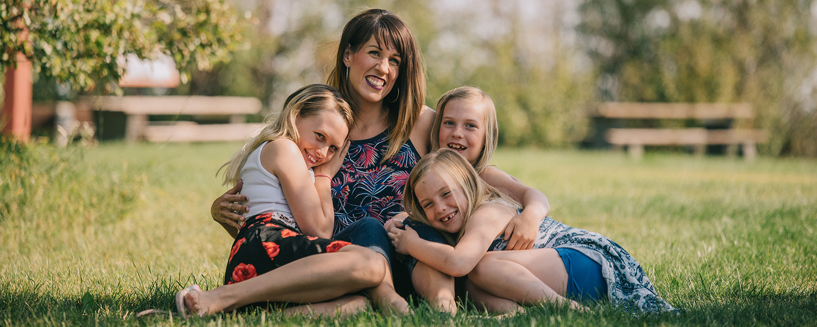 Eine sitzende Mutter umarmt ihre drei sitzende Töchter