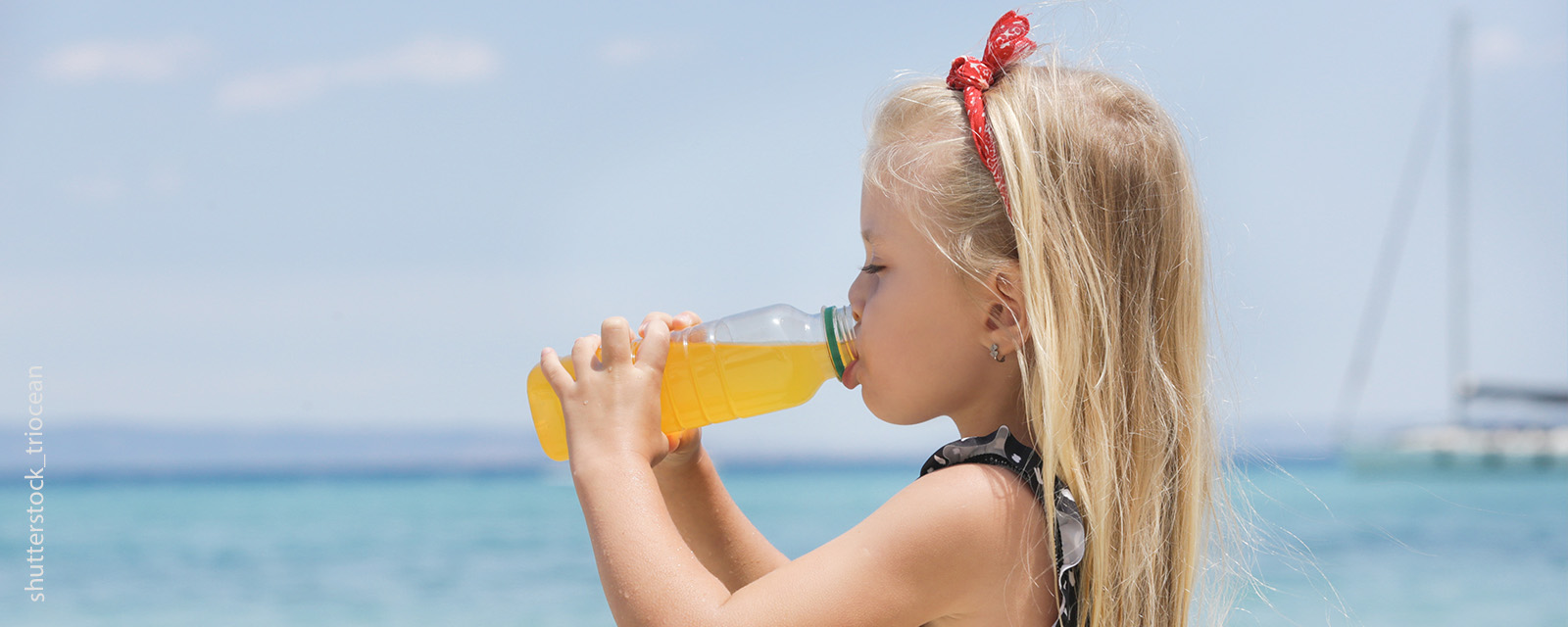 Ein Mädchen trinkt einen Saft am Meer