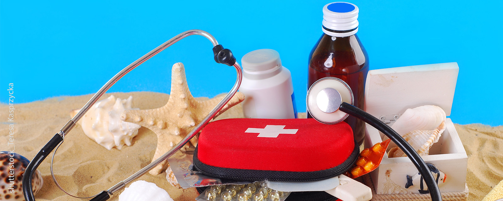 Reiseapotheke, Stethoskop und weitere Medikamente befinden sich auf einem Strand