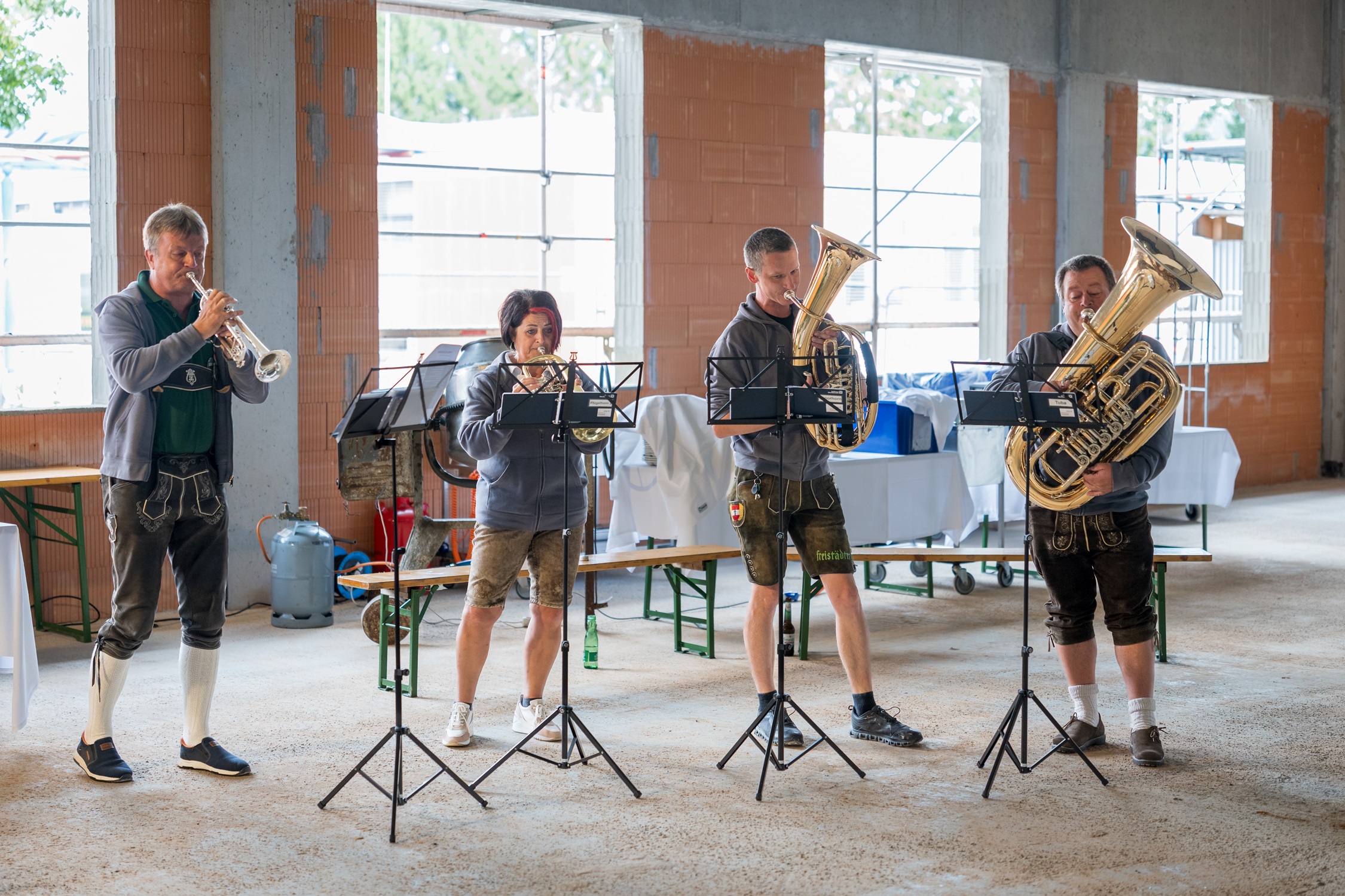 Blaskapelle spielt in Lederhosen in einem Rohbau in Österreich.