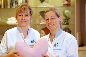 Zwei Pflegerinnen halten ein rosa Herz