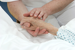 Pfleger hält Hand von Patientin